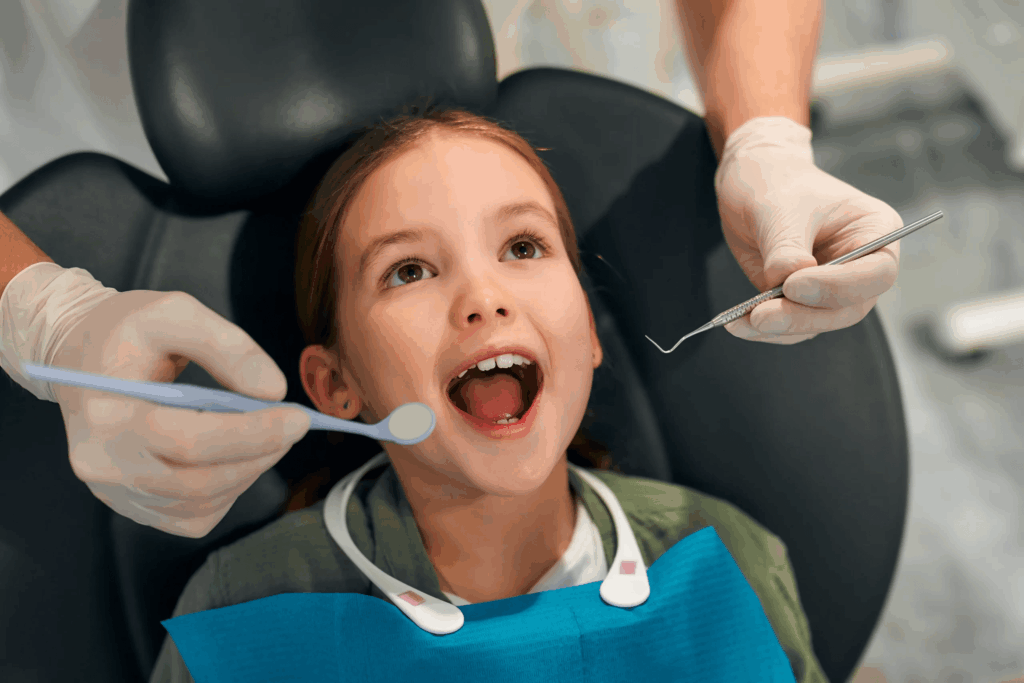 Niña sentada en el sillón durante una revisión con la dentista infantil