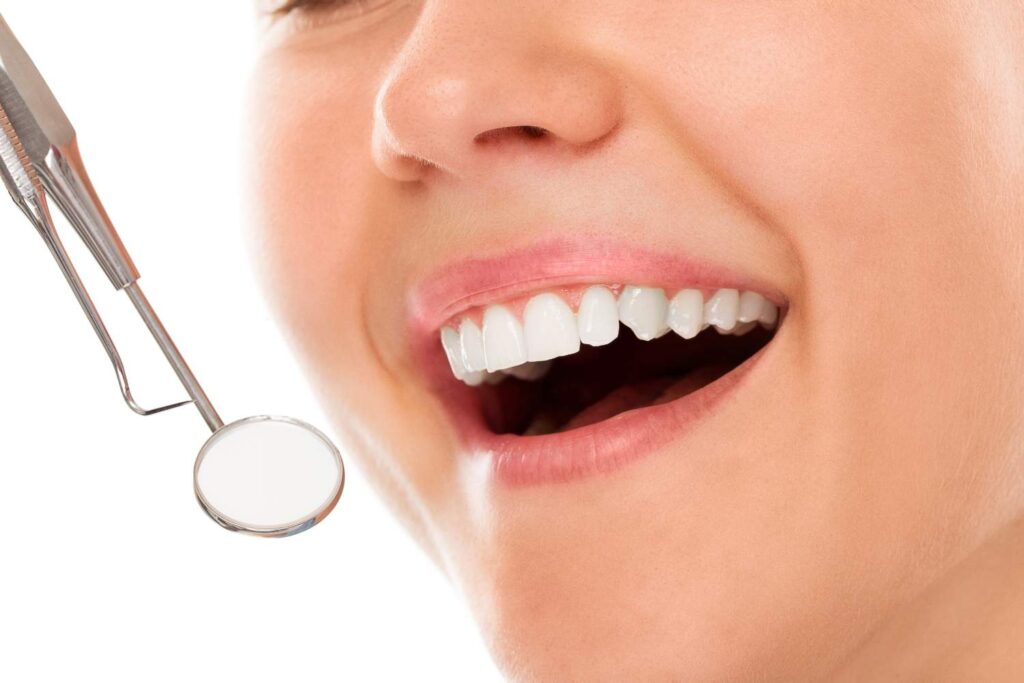 Sonrisa con dientes blancos y un espejo dental durante una revisión de estética