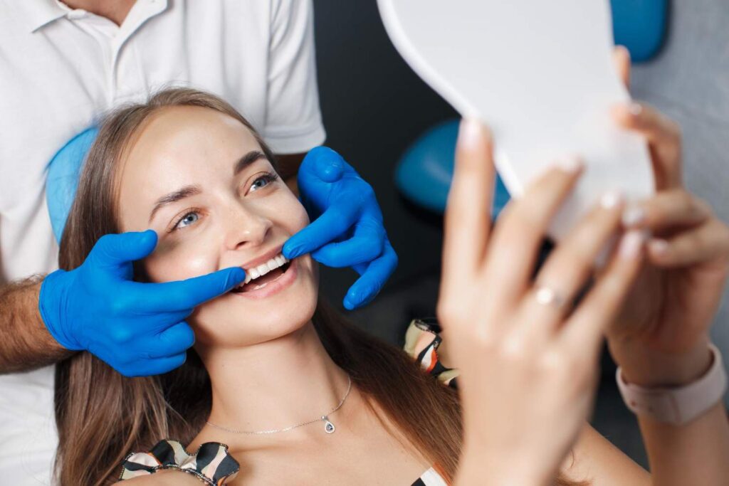 Paciente sonriendo y mirándose en un espejo durante una consulta de estética dental