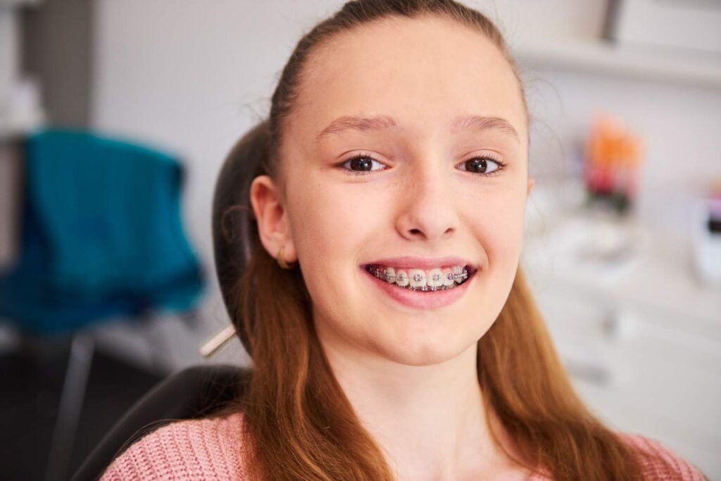 Adolescente sonriendo con brackets en la consulta del dentista